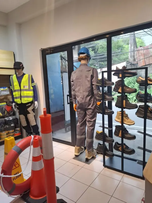 Mannequins en gilet et combinaison devant un présentoir de chaussures
